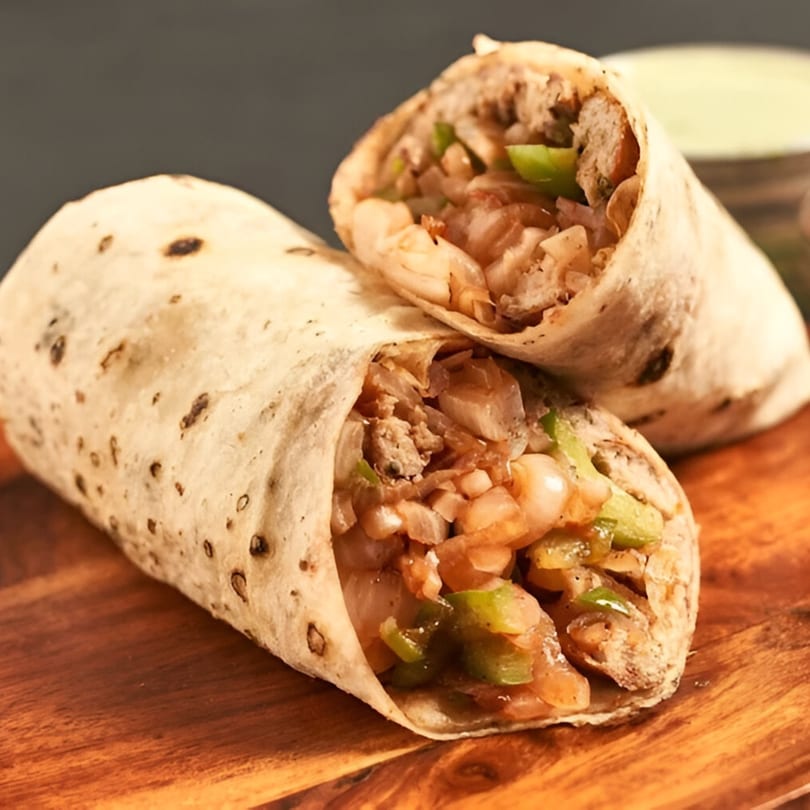 Two A1 Fusion Eats Midtown burritos, cut in half, filled with meat, onions, and green peppers.